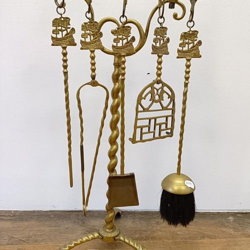 987 - A Dutch brass fire companion set, the stand with a large galleon finial, 120 cm high