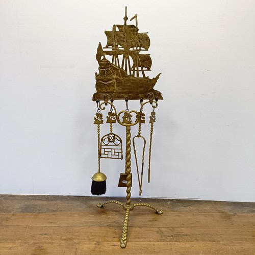 987 - A Dutch brass fire companion set, the stand with a large galleon finial, 120 cm high