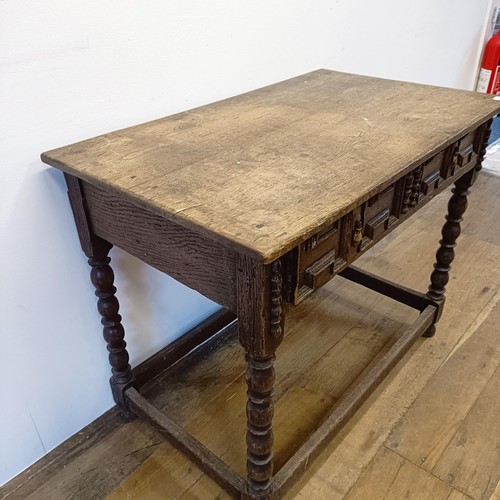 1008 - An oak side table, with a carved frieze drawer, on bobbin turned legs united by a stretcher, 90 cm w... 