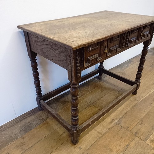 1008 - An oak side table, with a carved frieze drawer, on bobbin turned legs united by a stretcher, 90 cm w... 