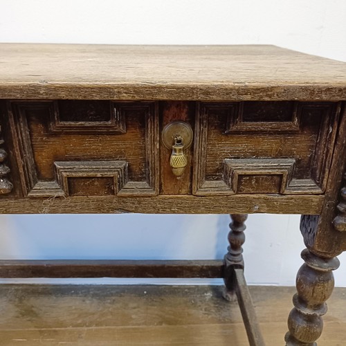 1008 - An oak side table, with a carved frieze drawer, on bobbin turned legs united by a stretcher, 90 cm w... 