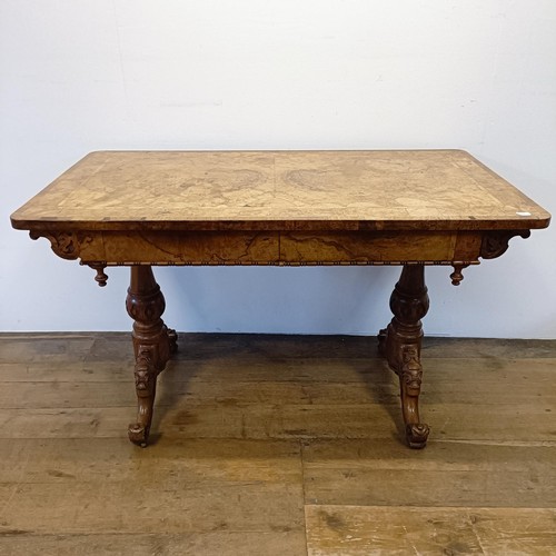 1010 - A late 19th/early 20th century walnut library table, with two frieze drawers, on carved twin end sup... 