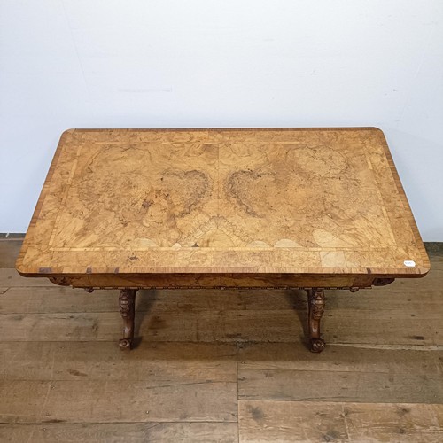 1010 - A late 19th/early 20th century walnut library table, with two frieze drawers, on carved twin end sup... 