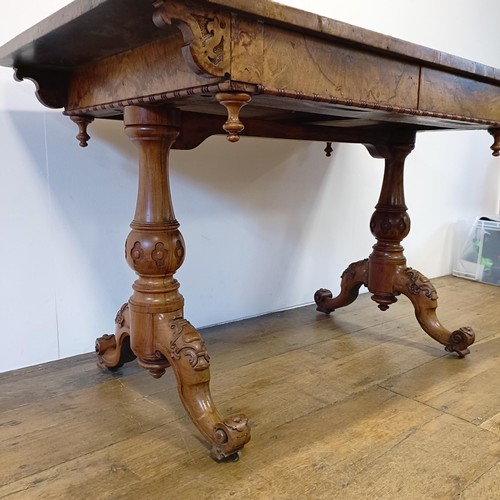 1010 - A late 19th/early 20th century walnut library table, with two frieze drawers, on carved twin end sup... 