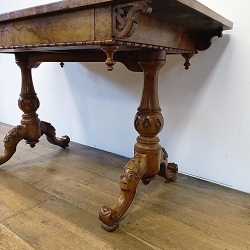 1010 - A late 19th/early 20th century walnut library table, with two frieze drawers, on carved twin end sup... 