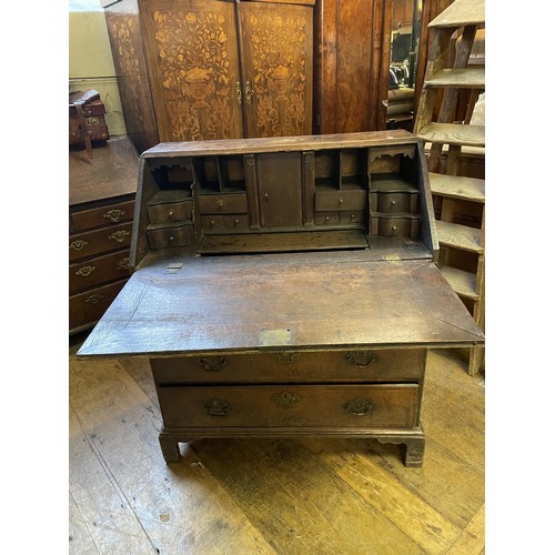 1021 - An 18th century oak and mahogany crossbanded bureau, the fall front revealling a well, drawers and p... 