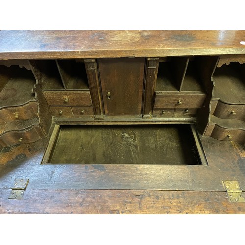 1021 - An 18th century oak and mahogany crossbanded bureau, the fall front revealling a well, drawers and p... 