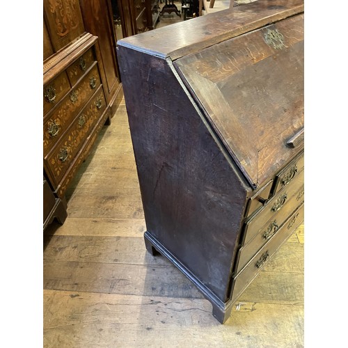 1021 - An 18th century oak and mahogany crossbanded bureau, the fall front revealling a well, drawers and p... 