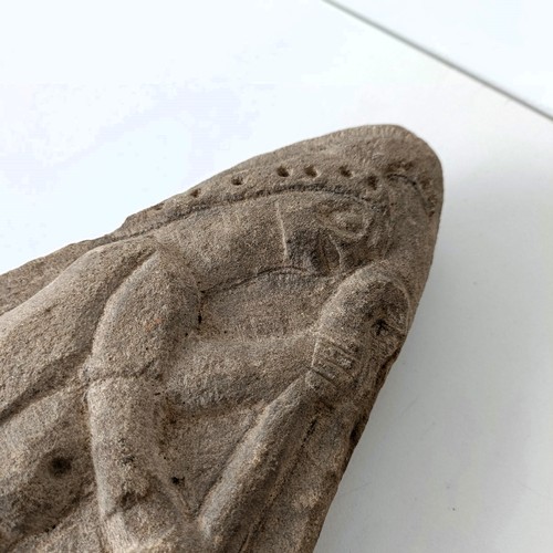 825 - A carved stone, of triangular form, decorated a figure, 22 cm high, and two other stone carvings (3)