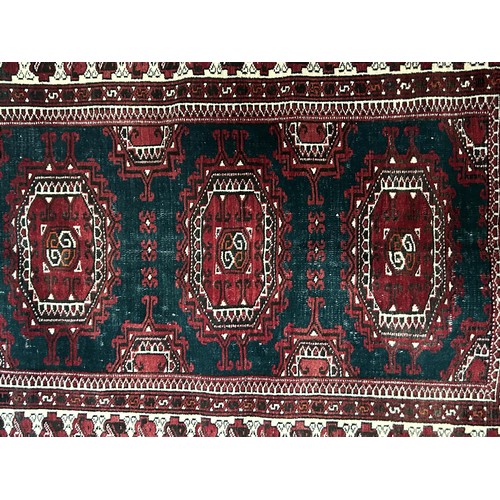 976 - An Afghan type rug, the central green ground with three medallions 140 x 100 cm