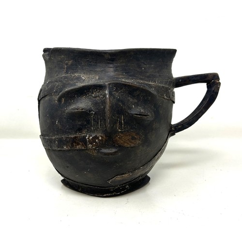 385 - A carved wood and metal bound jug, in the form of a face, 17 cm high