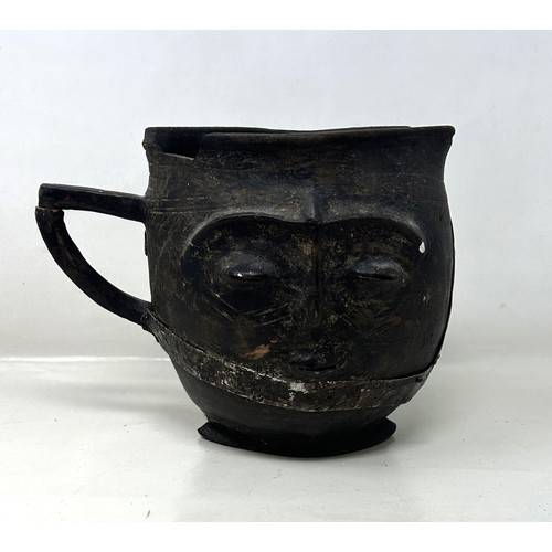 385 - A carved wood and metal bound jug, in the form of a face, 17 cm high