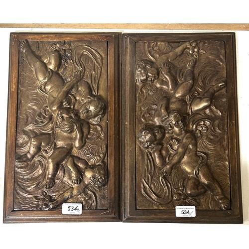 534 - A pair of brass plaques, decorated cherubs, in oak frames, 40 x 26 cm