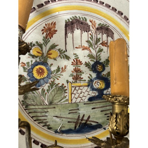 532 - A pair of Delft polychrome plates, decorated garden scenes, made into a pair of wall sconces with tw... 