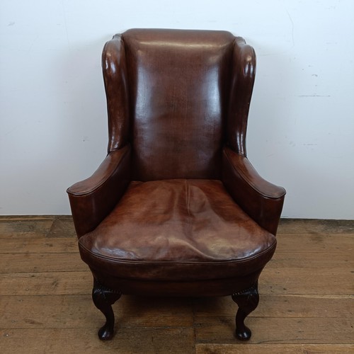 664 - An 18th century style wing armchair, with brown leather upholstery