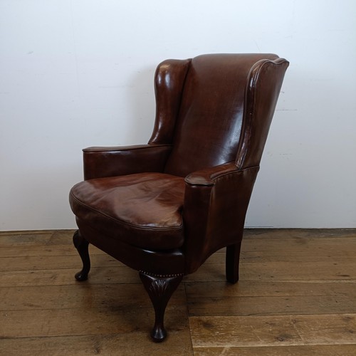 664 - An 18th century style wing armchair, with brown leather upholstery