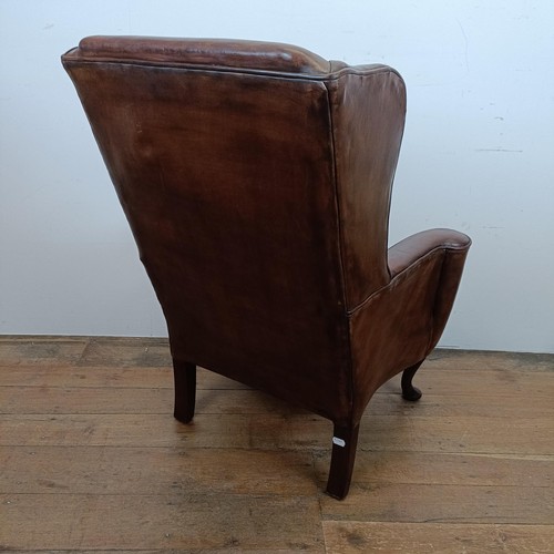 664 - An 18th century style wing armchair, with brown leather upholstery