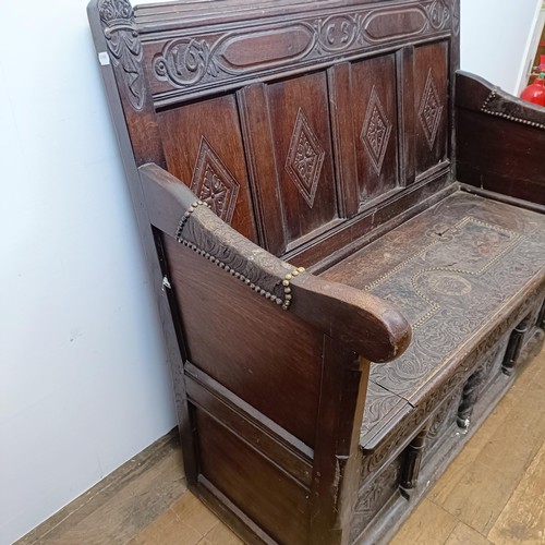 666 - A 17th century style carved oak settle, with a painted leather panel to the seat and arms, 130 cm wi... 