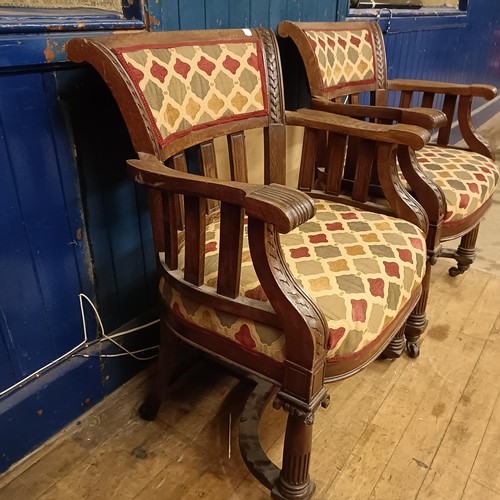 755 - A pair of late Victorian carved oak armchairs, with padded backs and seats, on ionic column legs to ... 