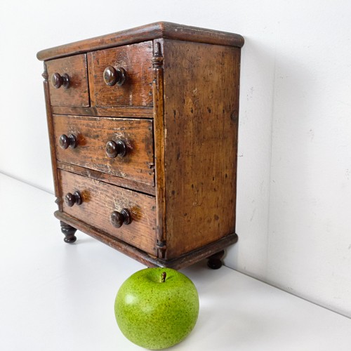 704 - A miniature table top pine chest, having two short and two long drawers, on turned feet, 30 cm high ... 