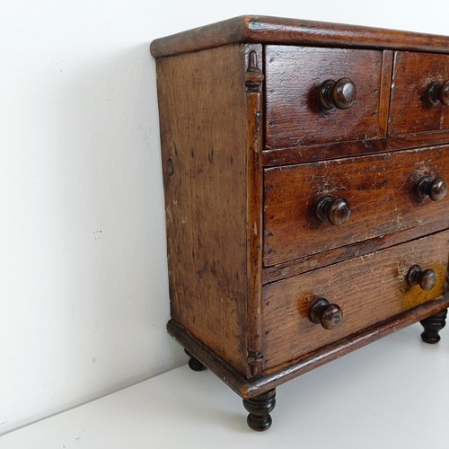 704 - A miniature table top pine chest, having two short and two long drawers, on turned feet, 30 cm high ... 