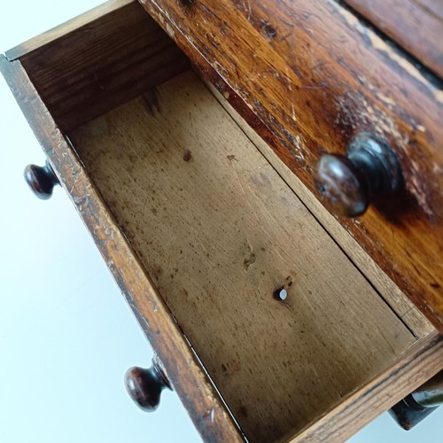 704 - A miniature table top pine chest, having two short and two long drawers, on turned feet, 30 cm high ... 