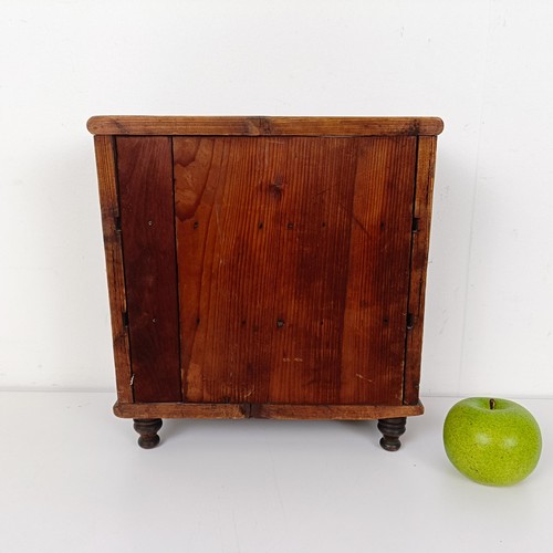 704 - A miniature table top pine chest, having two short and two long drawers, on turned feet, 30 cm high ... 