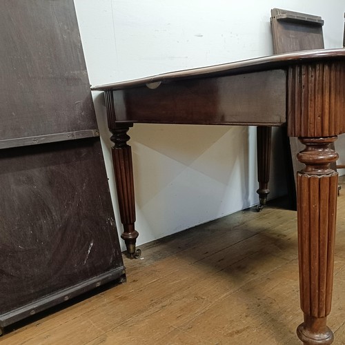 650 - A 19th century mahogany extending dining table, on turned reeded legs to castors, with four extra le... 