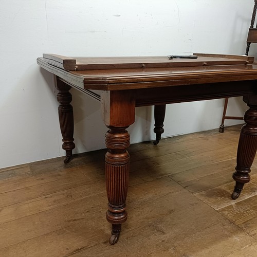 648 - A mahogany extending dining table, with an extra leaf, on turned tapering legs and castors, the top ... 