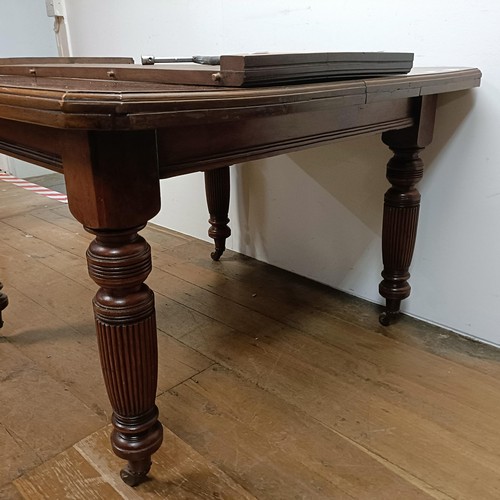 648 - A mahogany extending dining table, with an extra leaf, on turned tapering legs and castors, the top ... 