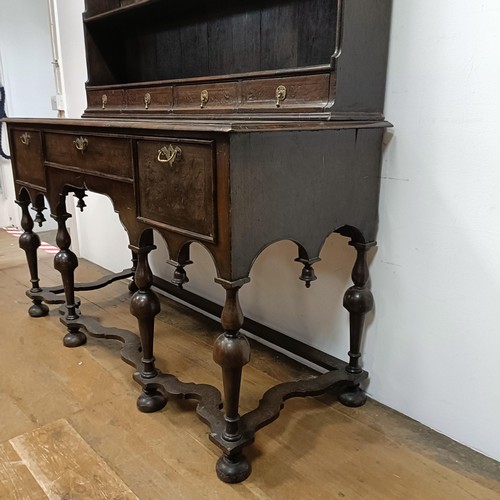 728 - An 18th century style dresser, veneered in walnut, having a three tier plate rack, on a base with th... 