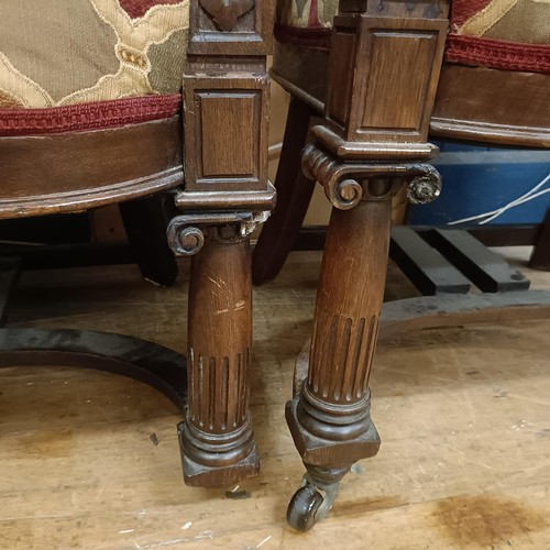 921 - A pair of late Victorian carved oak armchairs, with padded backs and seats, on ionic column legs to ... 