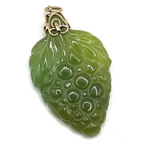 54 - A carved green stone pendant, decorated grapes, with a yellow metal mount