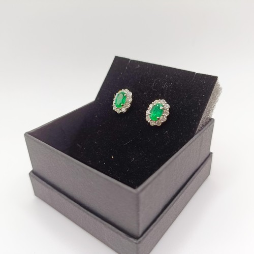 83 - A pair of 18ct white gold, oval emerald and RBC diamond cluster studs, boxed, emeralds 0.58ct, RBC d... 