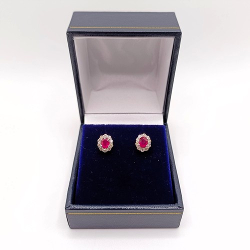 108 - A pair of 18ct white gold oval ruby and diamond cluster studs, boxed, rubies 0.60ct, R/C diamonds 0.... 