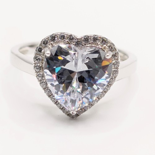 128 - A silver ring, with large heart shaped white CZ at the centre within a surround of smaller round CZs