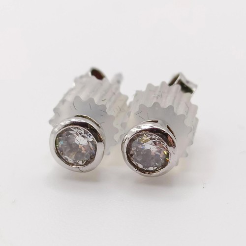 138 - A pair of silver solitaire studs, bezel set with white cubic zirconia, with plastic capped butterfly... 