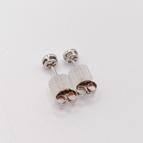 138 - A pair of silver solitaire studs, bezel set with white cubic zirconia, with plastic capped butterfly... 