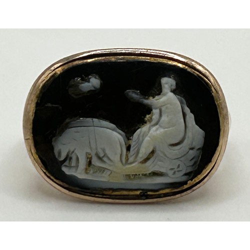 172 - An antique yellow metal ring, inset a carved cameo decorated figure and dogs, possibly Roman