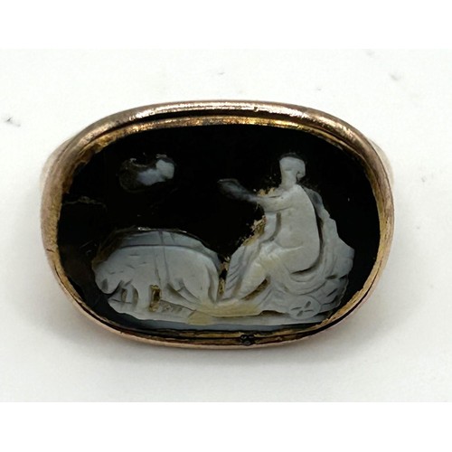 172 - An antique yellow metal ring, inset a carved cameo decorated figure and dogs, possibly Roman