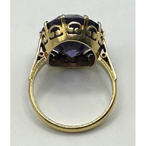 202 - A yellow coloured metal and purple stone ring, ring size M