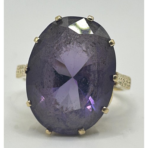 202 - A yellow coloured metal and purple stone ring, ring size M