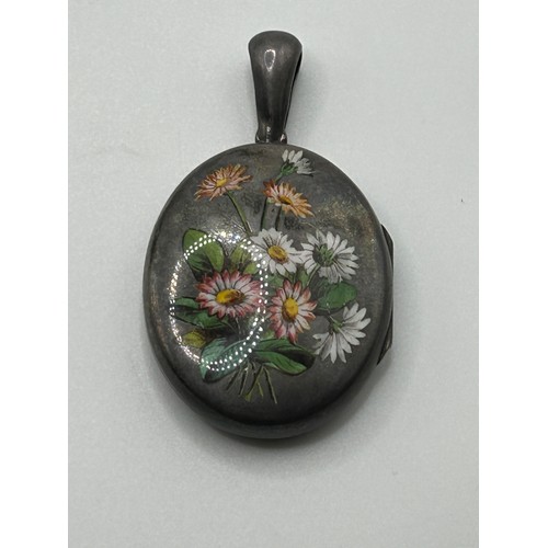 5 - A late 19th/early 20th century, silver coloured metal and enamel oval locket, decorated flowers