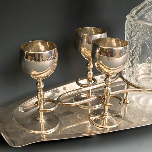 405 - A George V silver liqueur set, comprising a fitted tray, six goblets, and a cut glass decanter, Birm... 