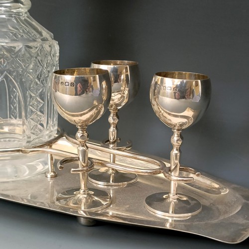 405 - A George V silver liqueur set, comprising a fitted tray, six goblets, and a cut glass decanter, Birm... 