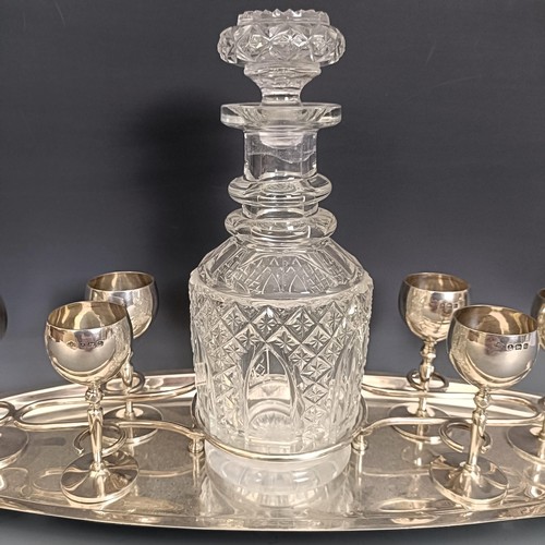 405 - A George V silver liqueur set, comprising a fitted tray, six goblets, and a cut glass decanter, Birm... 