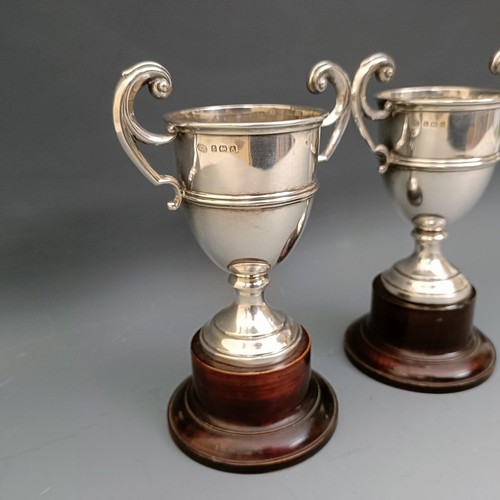 556 - A pair of modern silver two handled trophy cups, 4.7 ozt, 11.5 cm high, on turned wooden stands, Lav... 