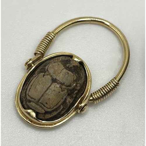 27 - A yellow coloured metal hinged ring, inset with a scarab, the undersigned with hieroglyphics, ring s... 