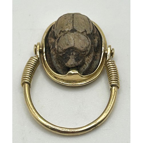 27 - A yellow coloured metal hinged ring, inset with a scarab, the undersigned with hieroglyphics, ring s... 