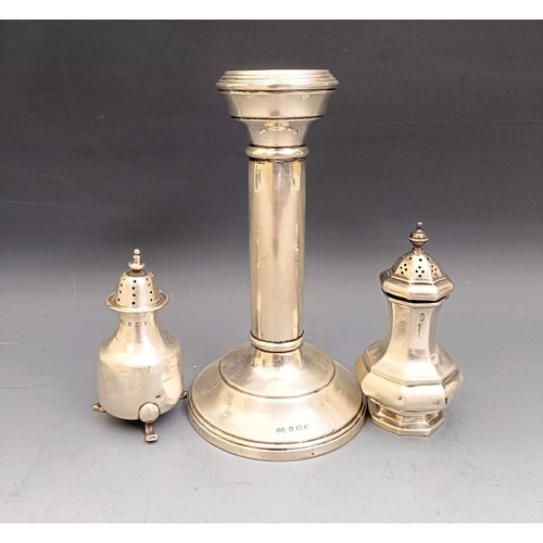 580 - A George V silver candlestick, base filled, and two pepperpots, various dates and marks